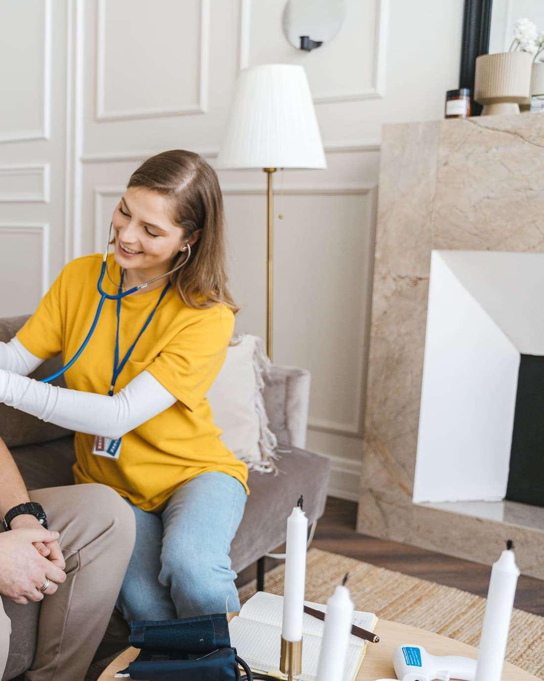 A nurse listening to an elderly man’s chest with a stethoscope in his living room
